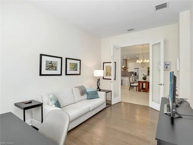 Den featuring french doors, wood finished floors, visible vents, and a notable chandelier