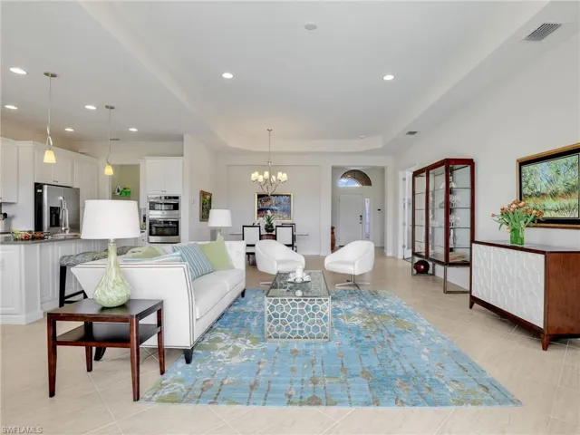Living room featuring recessed lighting, visible vents, an inviting chandelier, a tray ceiling, and light tile patterned flooring