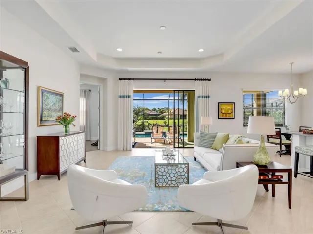 Living room with an inviting chandelier, baseboards, and a tray ceiling