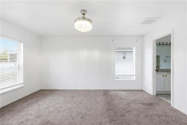 Carpeted empty room with suspended lighting and baseboards