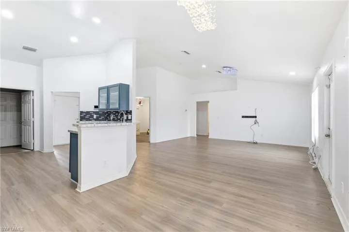 Kitchen with open floor plan, lofted ceiling, recessed lighting, light stone countertops, and light wood-style floors