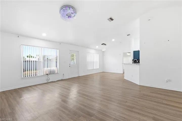 Unfurnished living room featuring vaulted ceiling, dark wood finished floors, and recessed lighting