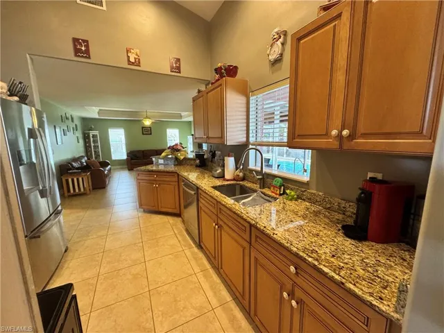 Kitchen featuring light stone countertops, wood finish cabinetry, stainless steel appliances, and light tile patterned flooring
