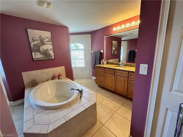Full bathroom featuring vanity, a garden tub, light tile patterned floors, and a walk in shower