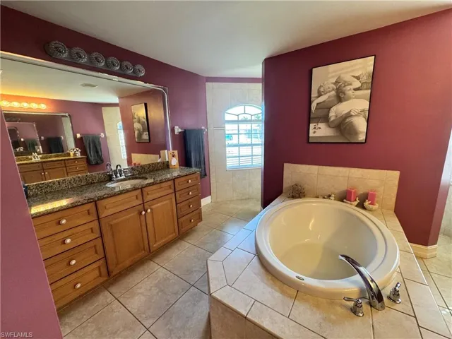 Full bath with vanity, a garden tub, and light tile patterned floors