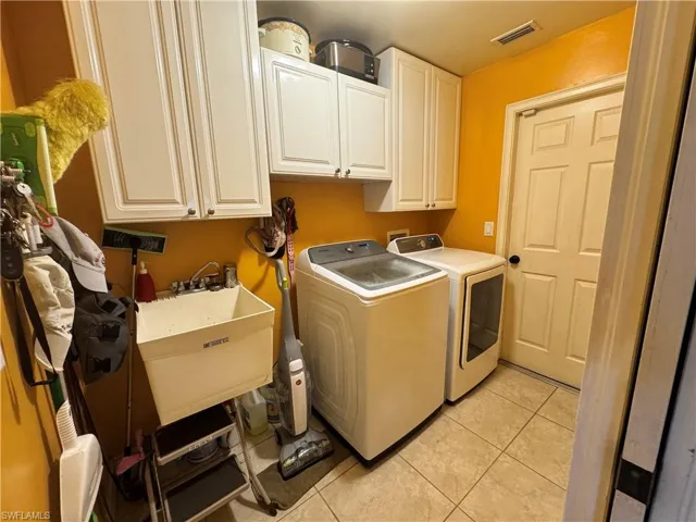 Laundry room featuring cabinet space, separate washer and dryer, and light tile patterned floors