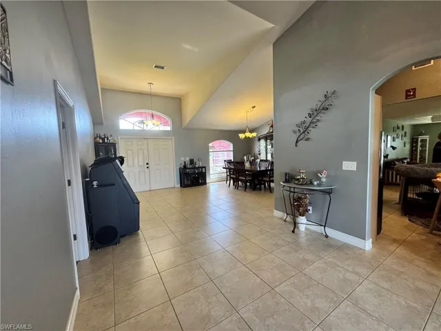 Foyer entrance featuring arched walkways, light tile patterned flooring, and vaulted ceiling