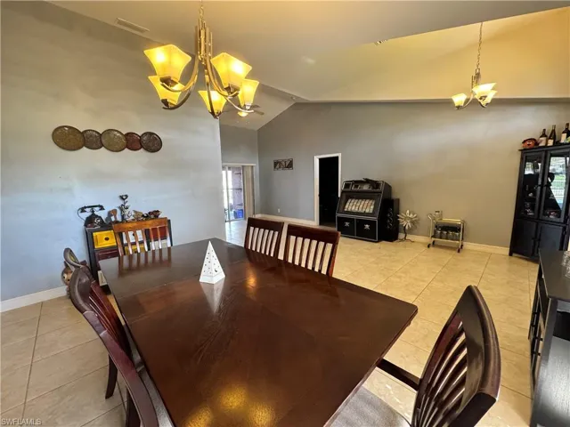 Dining space featuring suspended lighting, vaulted ceiling, and light tile patterned flooring