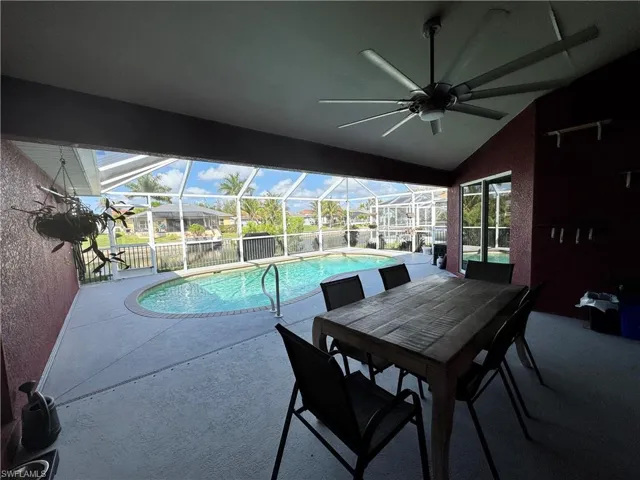 Swimming pool with a patio area, glass enclosure, a sunroom, outdoor dining area, and a residential view
