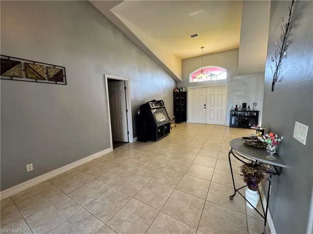 Foyer with light tile patterned floors and vaulted ceiling