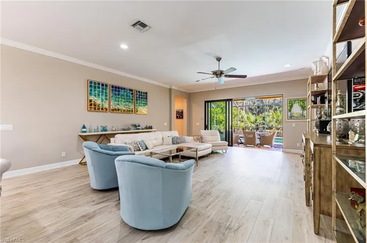 Living room with ornamental molding, light hardwood / wood-style floors, and ceiling fan