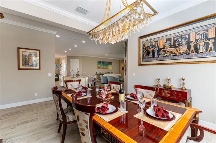 Dining room featuring hardwood / wood-style flooring, ornamental molding, sink, and a chandelier
