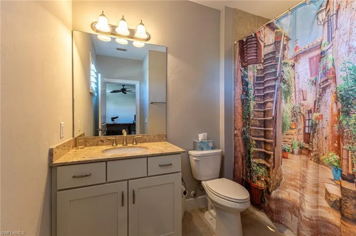 Bathroom featuring ceiling fan, vanity, toilet, and curtained shower