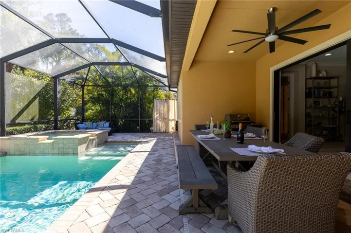 View of swimming pool with a grill, an in ground hot tub, ceiling fan, glass enclosure, and a patio area
