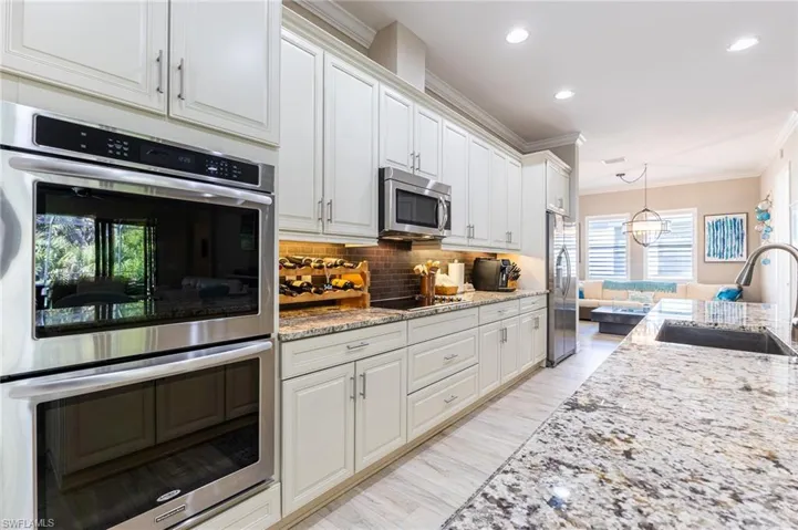 Kitchen featuring white cabinetry, appliances with stainless steel finishes, sink, and pendant lighting