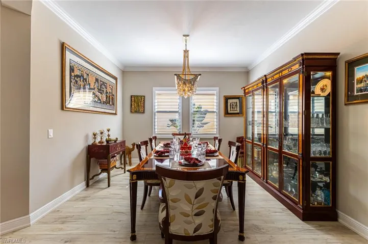 Dining area with crown molding, a notable chandelier, and light wood-type flooring