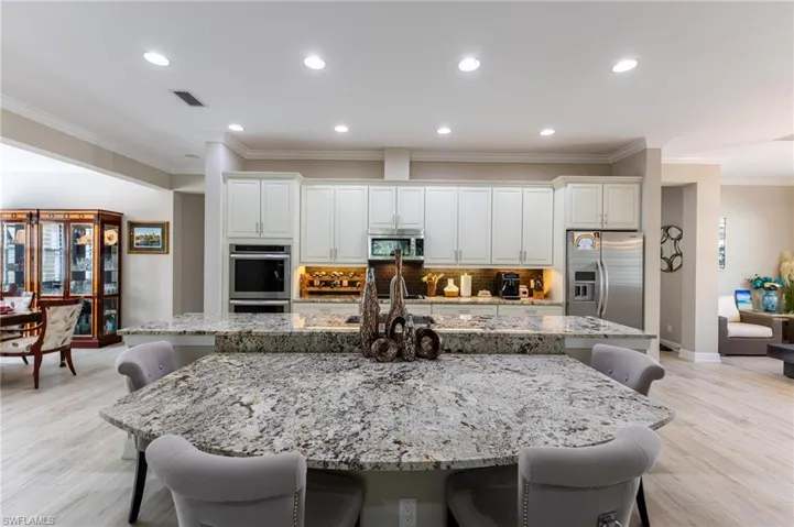 Kitchen with light stone counters, stainless steel appliances, a kitchen breakfast bar, and a spacious island