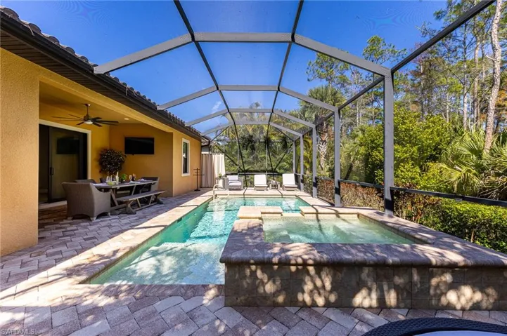 View of pool with a lanai, a patio area, ceiling fan, and an in ground hot tub