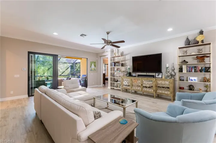 Living room with ornamental molding, ceiling fan, and light hardwood / wood-style floors