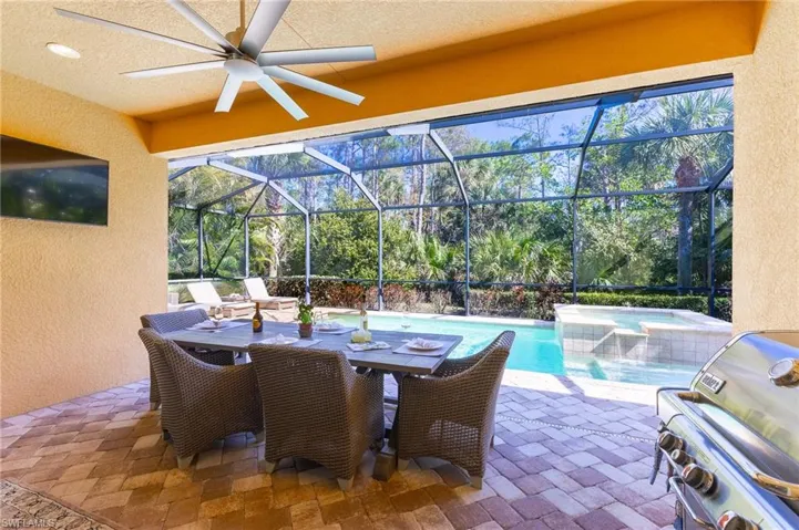 View of patio / terrace with ceiling fan, a grill, a lanai, and a pool with hot tub