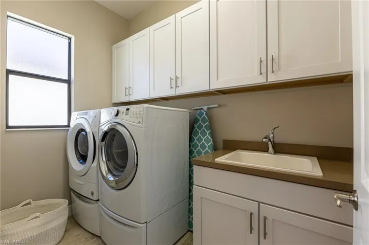 Laundry room with cabinets, sink, and washer and clothes dryer