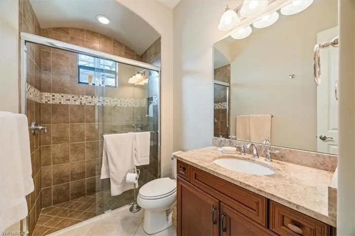 Bathroom featuring a shower stall, toilet, vanity, and tile patterned floors