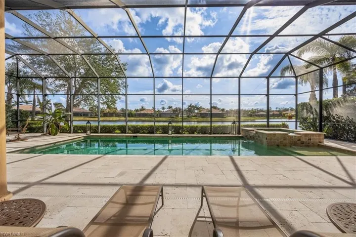 View of pool featuring a patio area, a lanai, a pool with connected hot tub, and a water view