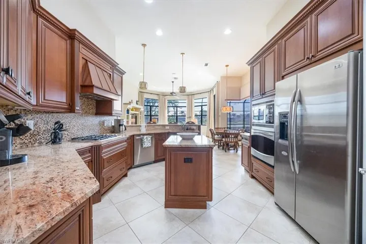 Kitchen with a center island, custom exhaust hood, recessed lighting, backsplash, and appliances with stainless steel finishes