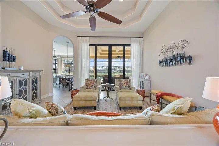 Living room featuring ceiling fan, tile patterned flooring, and a tray ceiling