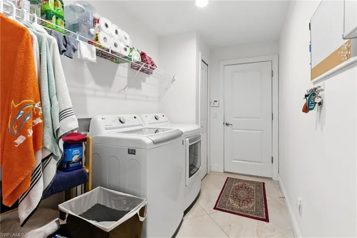 Washroom featuring light tile patterned flooring, washing machine and clothes dryer, and recessed lighting