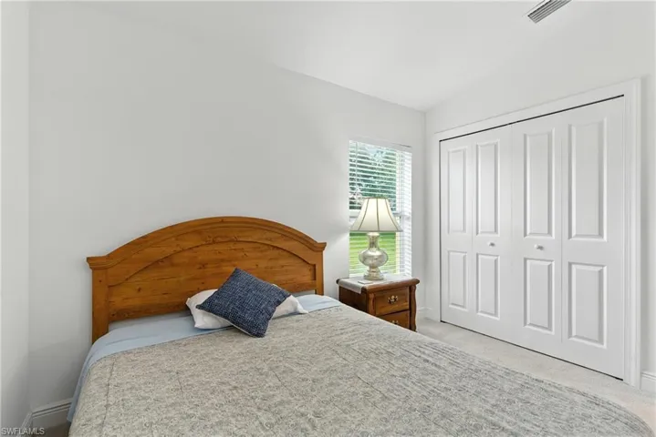 Bedroom featuring light carpet, a closet, and vaulted ceiling