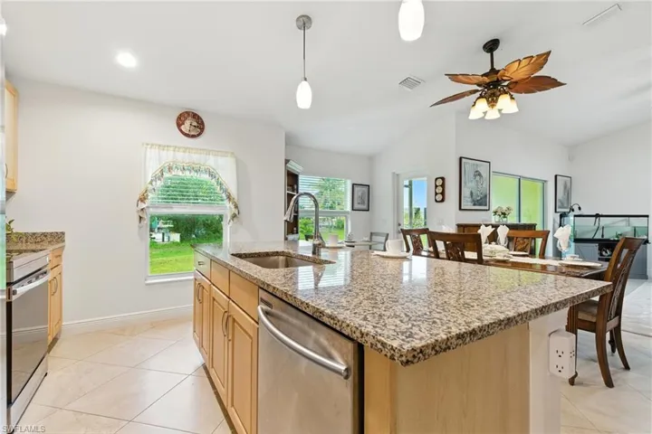 Kitchen featuring light stone countertops, appliances with stainless steel finishes, light brown cabinets, hanging light fixtures, and recessed lighting