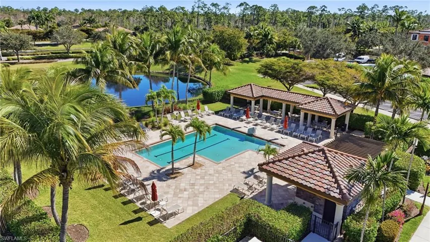 Community pool with a patio, view of scattered trees, a water view, and a lawn