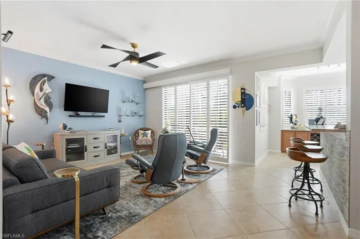 Living area with ornamental molding, light tile patterned floors, and ceiling fan