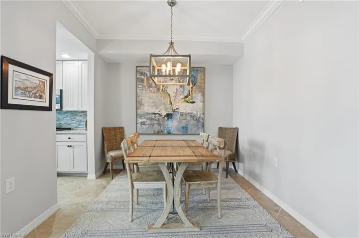 Dining space with crown molding, hanging lights, and light tile patterned floors