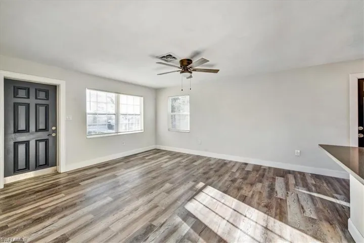 Unfurnished living room with ceiling fan, wood finished floors, and baseboards