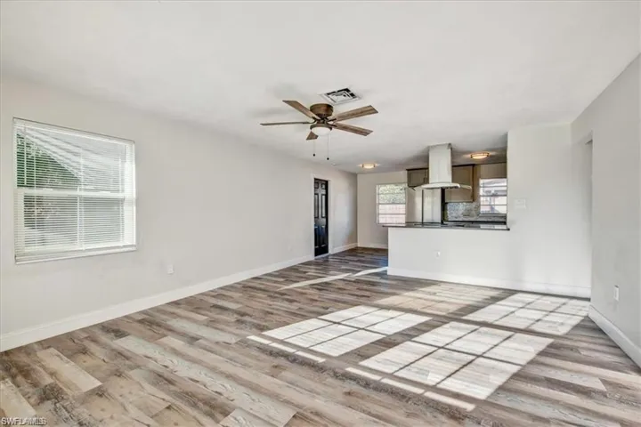 Unfurnished living room with wood finished floors, baseboards, and a ceiling fan