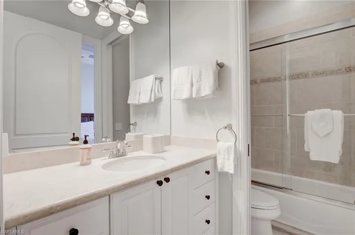 Full bathroom featuring vanity, toilet, and bath / shower combo with glass door