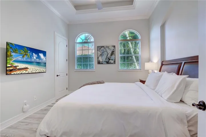 Bedroom featuring a raised ceiling, light hardwood / wood-style flooring, and ornamental molding