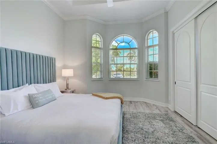 Bedroom with ceiling fan, light hardwood / wood-style floors, and multiple windows