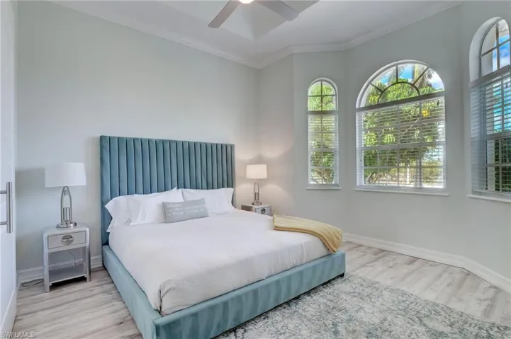 Bedroom with ceiling fan, light wood-type flooring, and ornamental molding