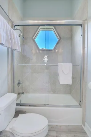 Bathroom with enclosed tub / shower combo and toilet