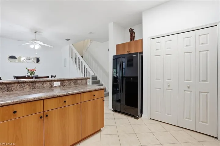 Kitchen area featuring light wood-finish cabinetry, a patterned countertop, pantry and a black refrigerator