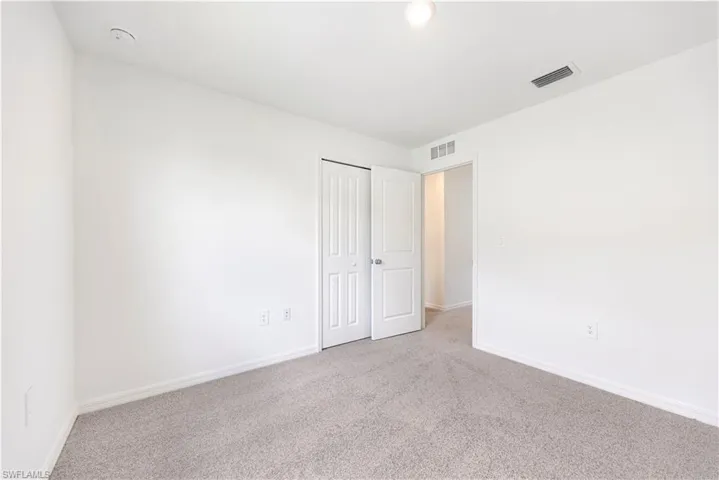 Unfurnished bedroom with light colored carpet and a closet