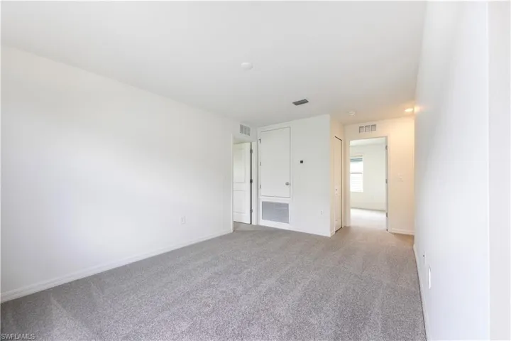 Unfurnished room featuring light carpet and baseboards