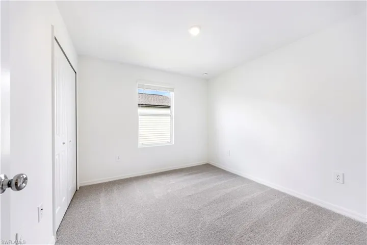 Unfurnished bedroom with light colored carpet and a closet