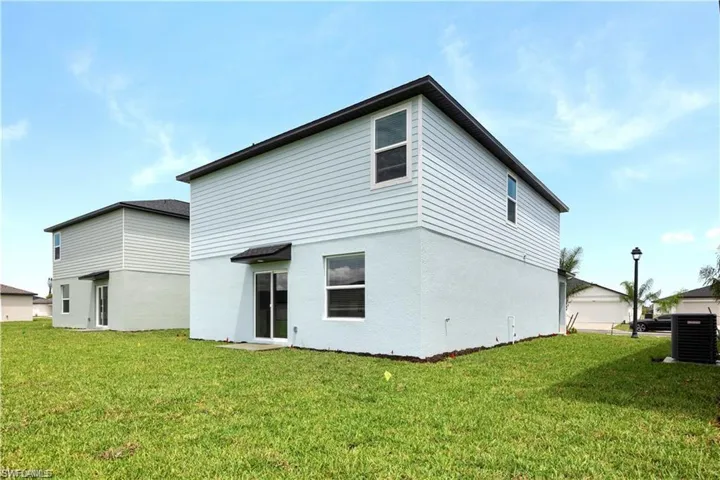 Back of property featuring a lawn and stucco siding