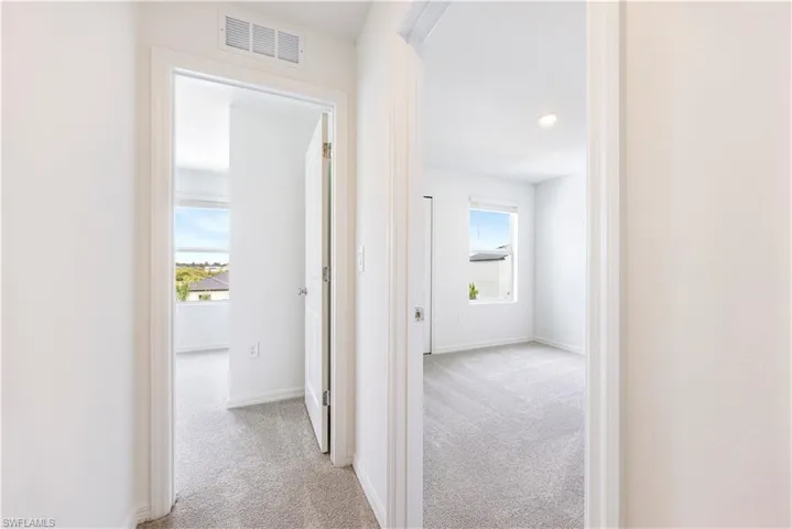 Hallway featuring light colored carpet and baseboards