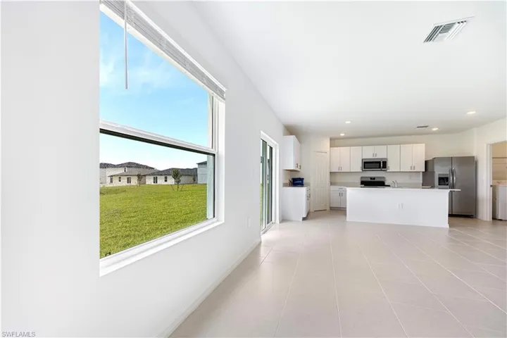Kitchen with stainless steel appliances, light countertops, white cabinetry, a center island with sink, and recessed lighting