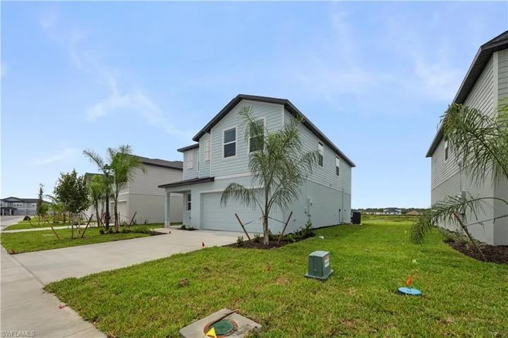View of side of home featuring an attached garage, concrete driveway, and a yard